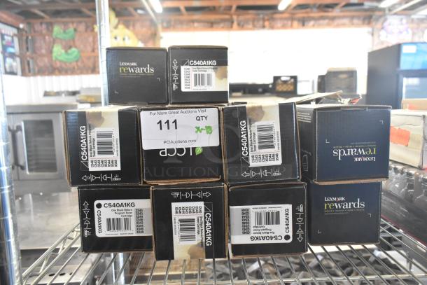 Boxes of Lexmark C540A1KG ink cartridges on a metal shelf, labeled for auction lot "111." Items appear new in original packaging.
