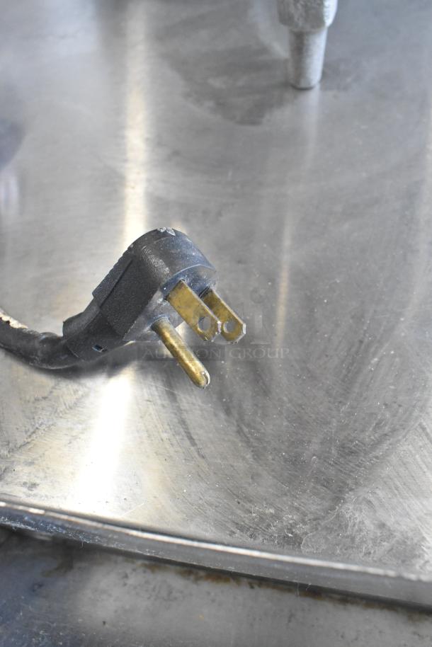 Power plug of Traulsen RHT 2-32NUT cooler. 115 volts, 1 phase. Black with gold prongs on a metallic surface.