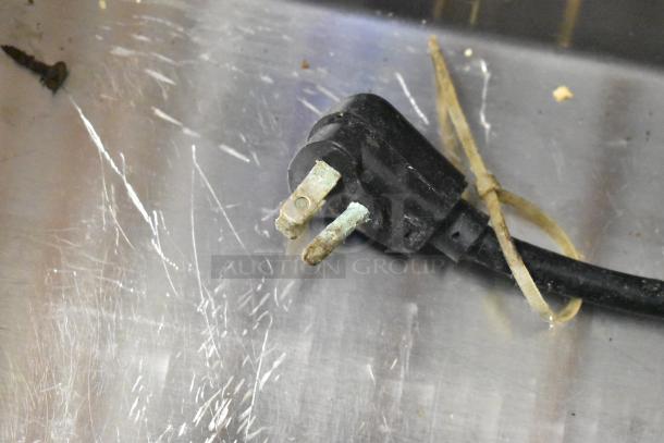 Close-up of a power plug for a Glastender FRM-2 commercial mobile ice cream freezer, showing oxidized prongs and wire tie.