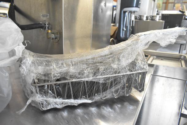 Three kitchen items wrapped in plastic: citrus juicer guard, meat grinder tray, taco shell fry basket. Auction item.