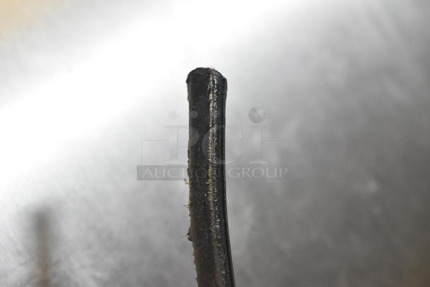 Black cylindrical object on reflective surface, possibly a part or tool. Close-up view showing texture and wear.