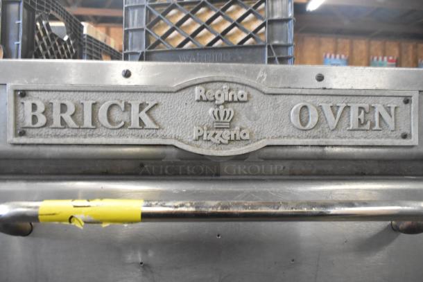 "Regina Pizzeria brick oven with metal signage and handle, featuring wear and yellow tape, for auction."