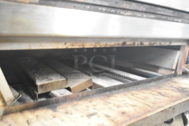 Two commercial single deck pizza ovens, stainless steel construction, showing signs of wear, suitable for high-volume use.