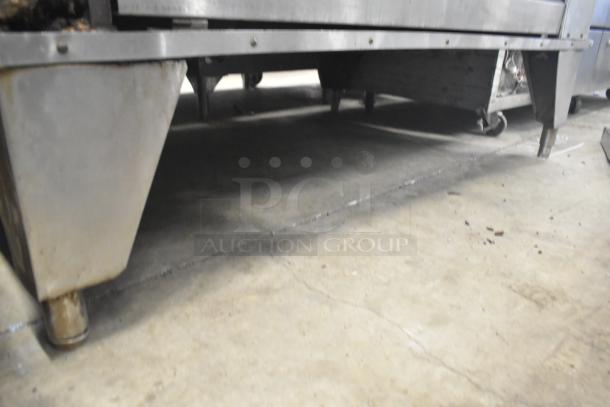 Dual commercial single deck pizza ovens, stainless steel, moderate wear. No visible labels or markings. Heavy-duty design.