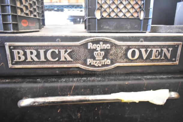 Commercial single deck pizza oven with "Regina Pizzeria" label and a metal handle, in used condition.