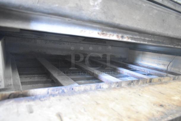 Two commercial single deck pizza ovens in fair condition, with visible wear and sturdy metal racks. Great for pizzerias.