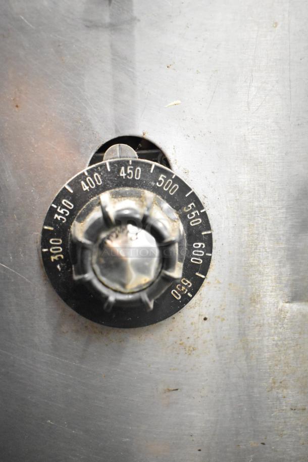 Montague 14-P-1 pizza oven temperature dial, showing 300-650°F settings. Stainless steel surface and signs of wear.