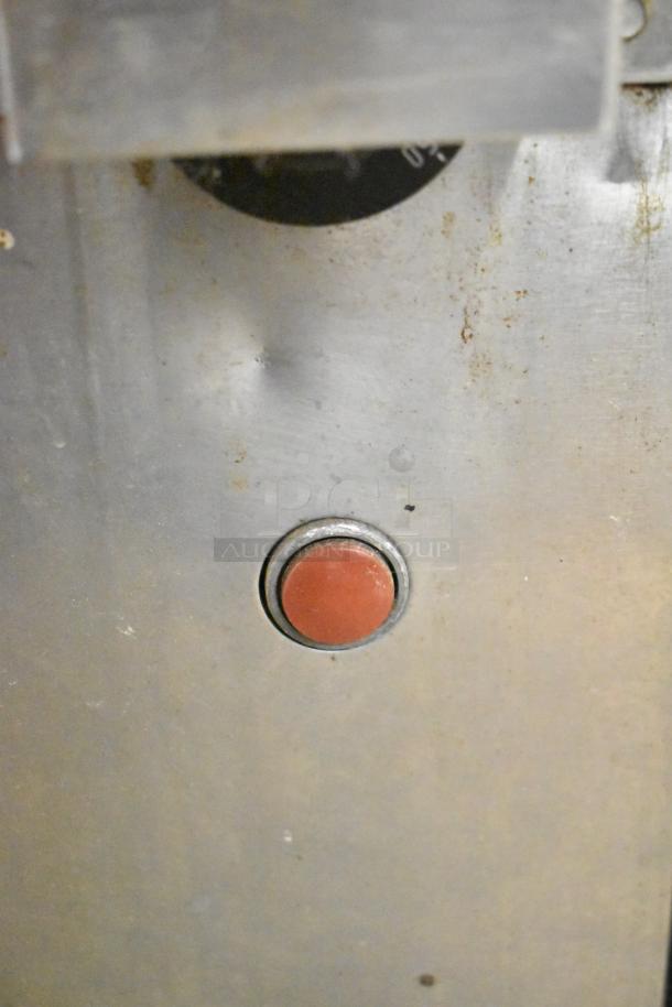 Montague 14-P-1 pizza oven detail showing metal surface with a red button. Auction includes two ovens with cooking stones.