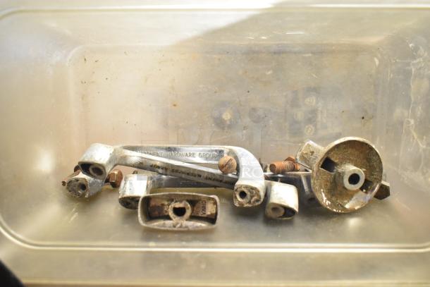 Assorted metal oven parts in a clear container, including handles and screws, showing signs of rust and wear.