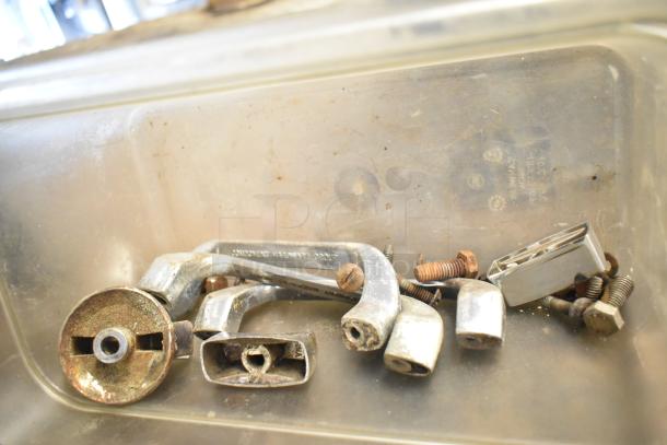 A bin containing metal hardware components, including handles and screws, possibly for assembling or maintenance purposes.