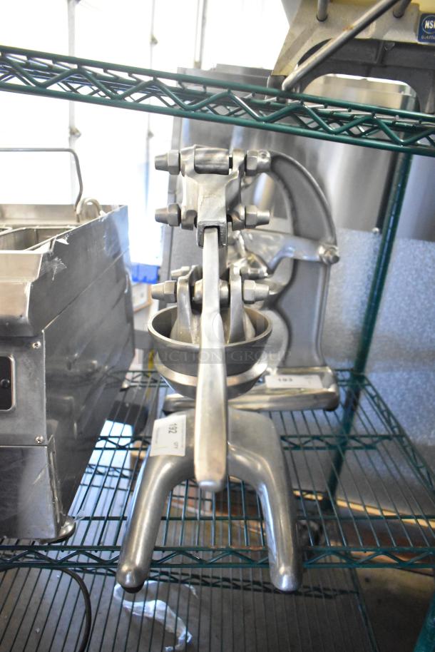 RA Chand Countertop Manual Citrus Juicer on metal shelf; stainless steel, good condition, heavy-duty lever, marked ID tag visible.