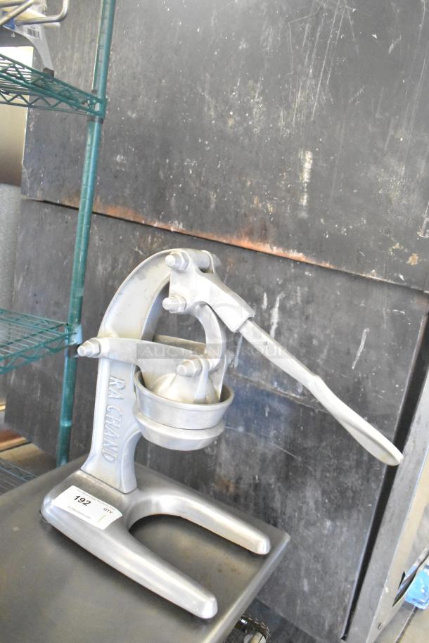 RA Chand countertop manual citrus juicer in metal, used condition. Visible brand name engraving. Auction tag attached.