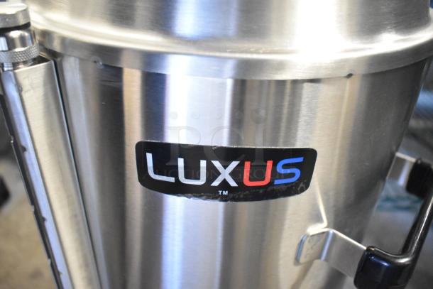Brand new Fetco TPD-30 Luxus 3-gallon stainless steel coffee dispenser with slight scratches, visible Luxus logo.