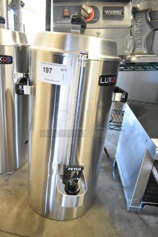 Brand new Fetco TPD-30 Luxus 3-gallon stainless steel coffee dispenser; minor scratches, auction tag visible.
