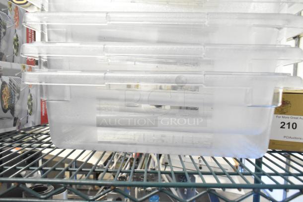 Six brand new clear poly bins, scratch and dent condition, stacked on a metal shelf. Auction tag partly visible.
