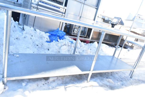Commercial steel table with under shelf, silver finish, sturdy metal legs, located outdoors in snow. Ideal for kitchens.