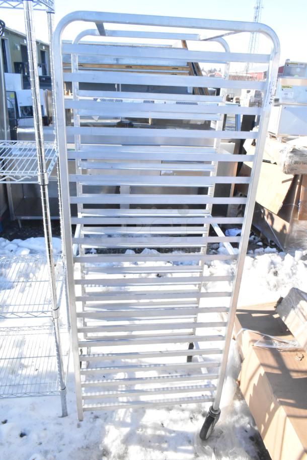 Commercial pan transport rack on durable casters, metal construction, multiple pan slots, used condition, outdoor setting.