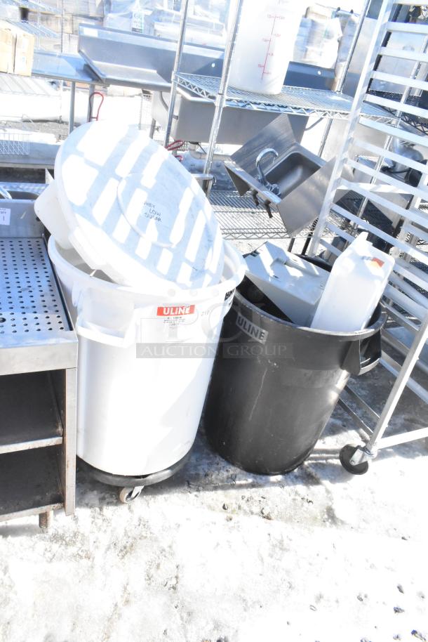 Two poly trash cans, white and black, labeled "ULINE," containing various materials, in fair condition.