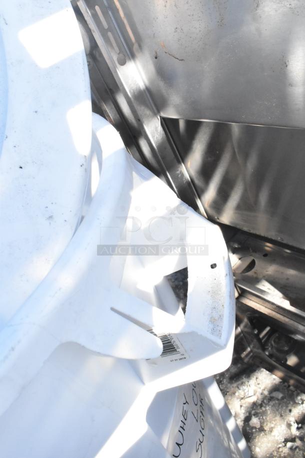 Two white poly trash cans with handles, containing various items, light dirt marks, one label visible.