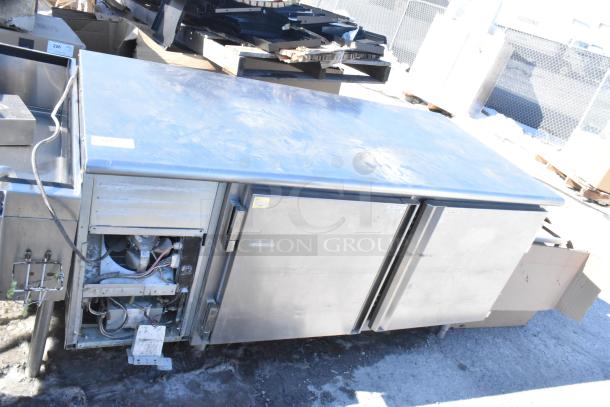 Commercial undercounter 2-door cooler with stainless steel finish. Visible wear includes minor scratches. Cooling unit access is open.