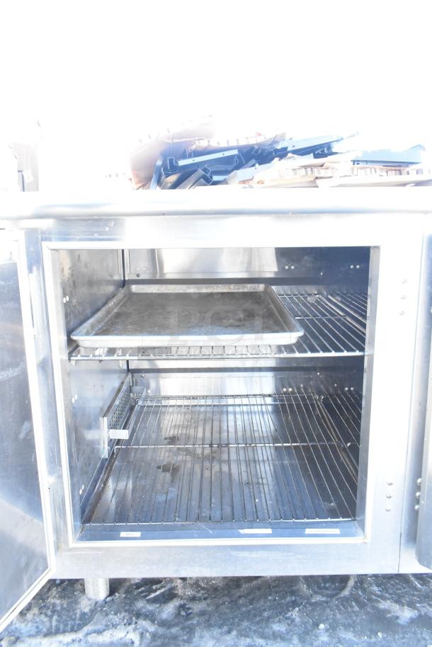 Commercial Undercounter 2 Door Cooler, stainless steel, with wire shelves and a baking tray, showing moderate use.