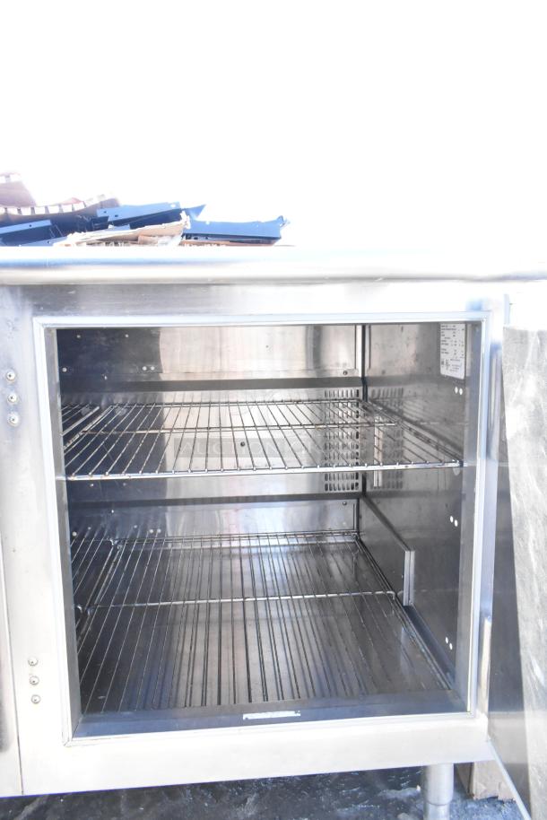 Commercial undercounter 2-door cooler with stainless steel finish, two wire shelves, in good condition.
