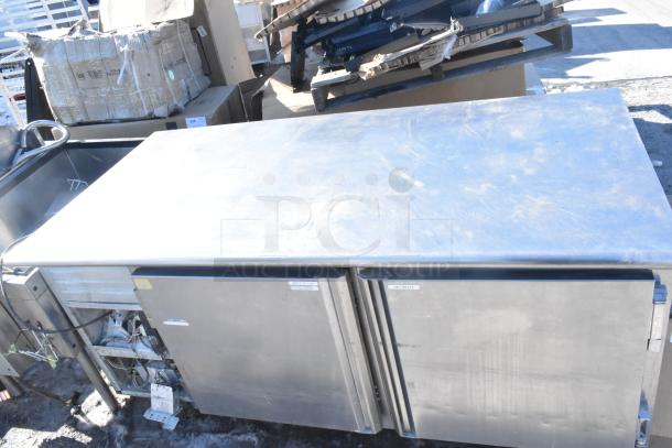 Commercial undercounter 2-door cooler; stainless steel, durable, used condition. Labels indicate sections for deli meats.