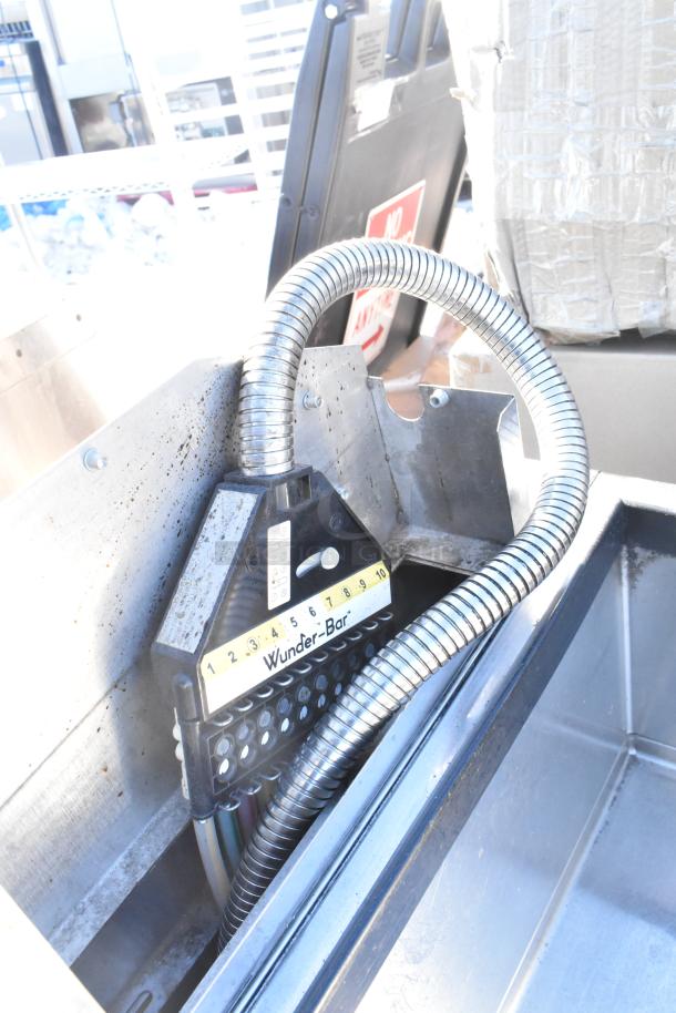 Commercial ice bin with Wunder-Bar soda gun, showing numbered buttons and spiral hose. Used condition, signs of wear.