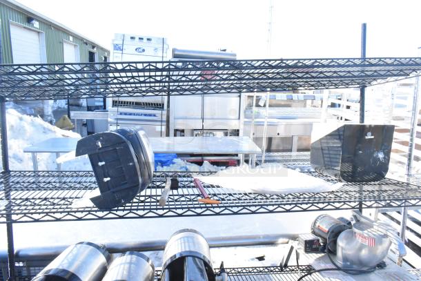 Black finish 4-tier wire shelving unit with napkin dispensers, outdoor setting, dismantling required by buyer.