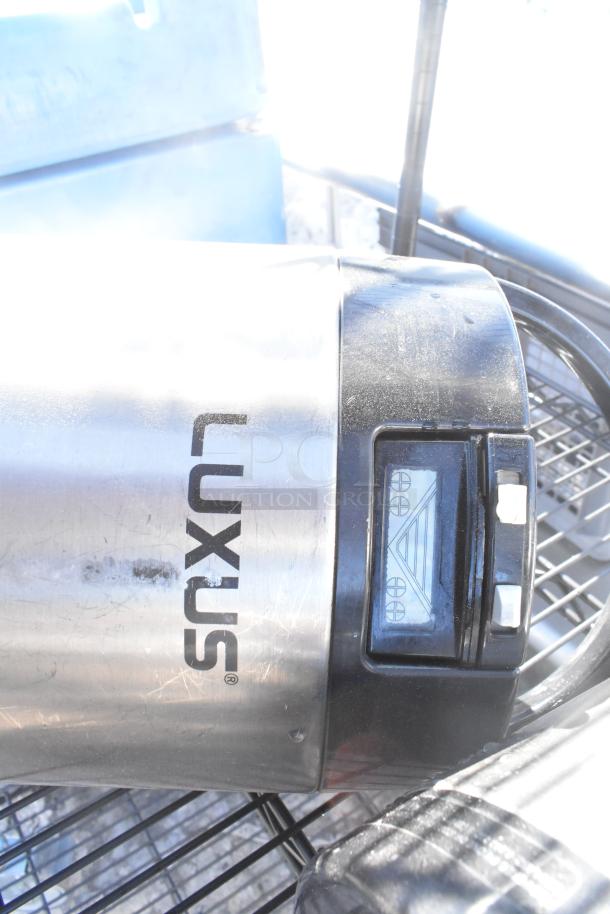 Black wire shelving unit with four tiers and napkin dispensers. Includes a stainless steel item labeled "LUXUS." Buyer to dismantle.