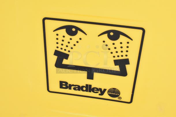 Bradley S19-921 Gravity Feed Eye Wash, yellow casing, clear Bradley logo. Safety equipment for emergency eye washing.