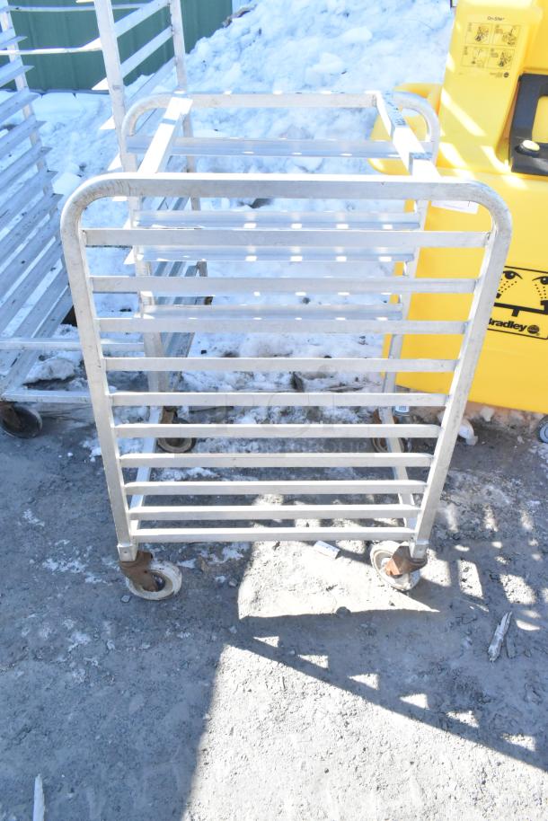 Commercial pan transport rack with multiple shelves and durable commercial casters, suitable for kitchen use. Visible wear.