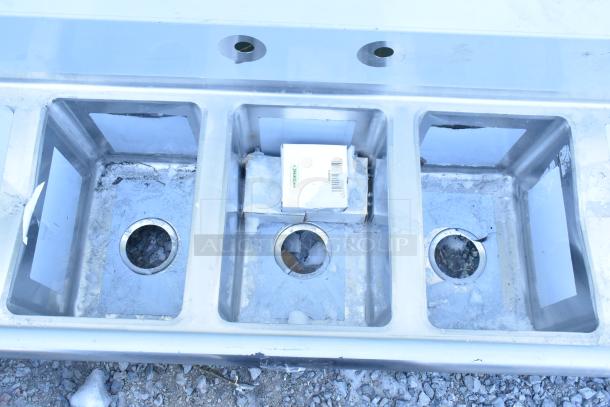 Brand new Regency 16-gauge stainless steel three-compartment sink with galvanized legs, two drainboards, and scratch and dent marks.