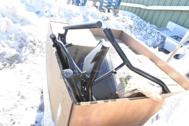 New scratch and dent items in a cardboard box, including a metal cart frame. Various parts visible, unopened condition.