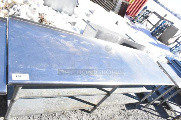 Commercial stainless steel table with two under shelves, in used condition. Visible tag shows lot number 254.