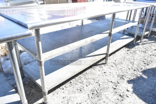 Commercial metal table with two under shelves, sturdy construction, used condition, suitable for kitchen or workshop.