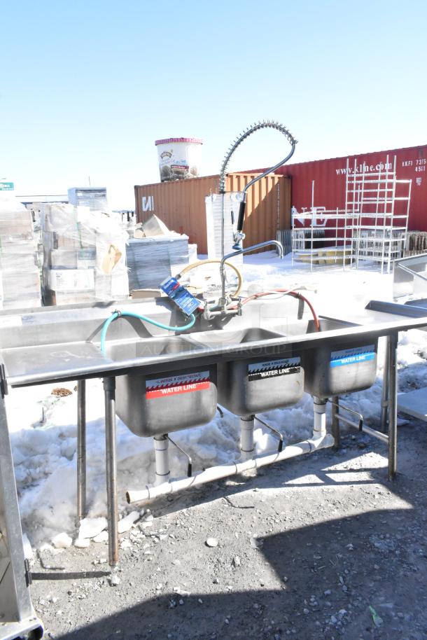 Commercial three-bay sink with dual drain boards, faucet, and spray nozzle. Labels indicate water line functions.