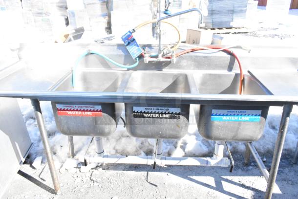 Commercial 3 bay sink with dual drain boards, faucet, handles, and spray nozzle. Labels indicate separate water lines.