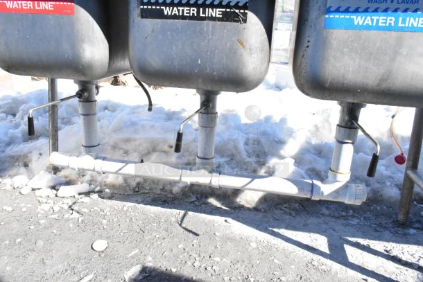 Commercial 3 bay sink with dual drain boards, featuring faucet, handles, and spray nozzle attachment. Visible "Water Line" labels.