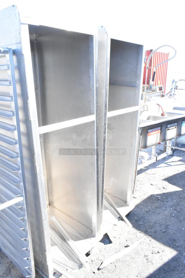 Two commercial pan transport racks on casters, metal construction, open-front design, likely for bakery or kitchen use.