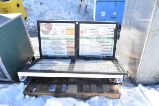 Outdoor menu sign on a pallet, featuring various sandwich options and prices. Slightly worn condition.
