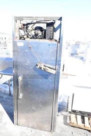 Commercial single door reach-in cooler, silver finish, visible wiring and components, fair used condition, label indicates model details.