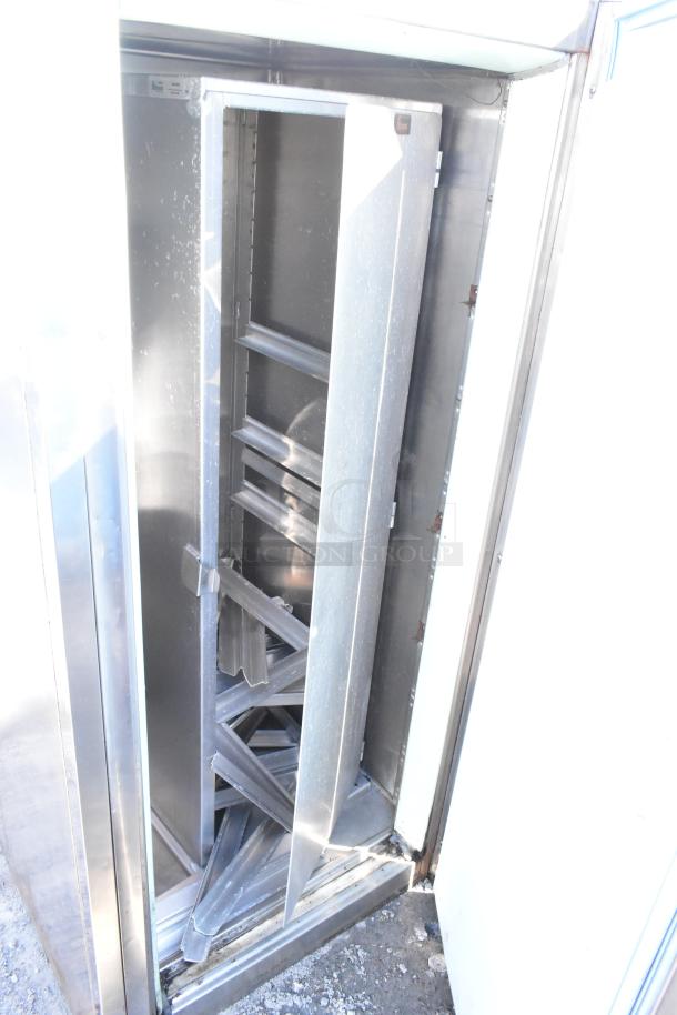 Commercial single door reach-in cooler in silver finish, featuring internal shelving. Visible wear, ideal for storage.