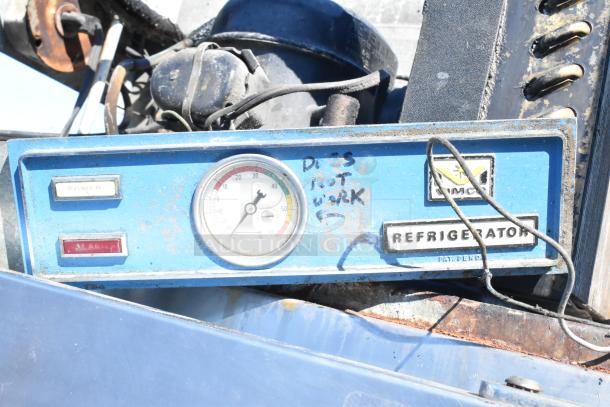 Old commercial single door reach-in cooler panel with a worn, blue control box. Gauge and markings indicate condition issues.