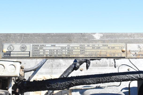 Alt text: Label on a Commercial Single Door Reach In Cooler indicates model A135-IDPS2, power supply 115V, and factory test pressure.