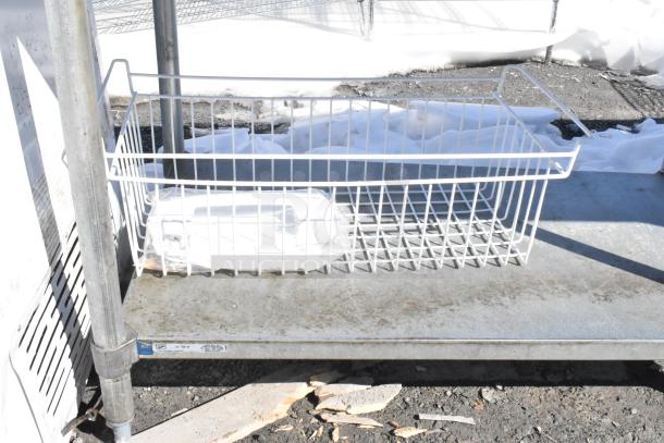Commercial table with metal under shelf, showing a white wire basket on top. Appears sturdy with minor wear.