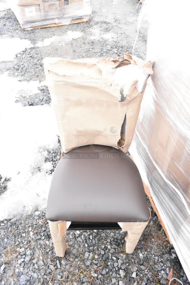 New chair with brown seat, covered in damaged brown wrapping, on a pallet outdoors. Part of scratch and dent auction.