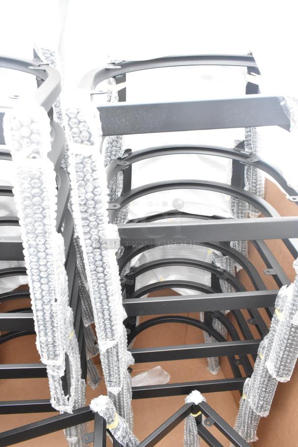 12 brand new scratch and dent chair frames, black metal, bubble wrapped for protection, stacked in a cardboard box.