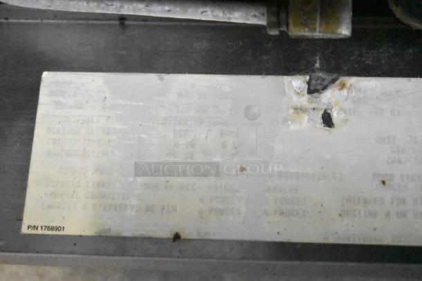 Metal plate with worn text and serial number on a Garland SunFire convection oven, indicating model details and specifications.