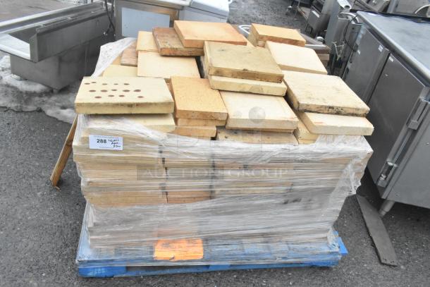 200 cooking stones for pizza oven, stacked on a pallet, various shapes and conditions, auction label visible.
